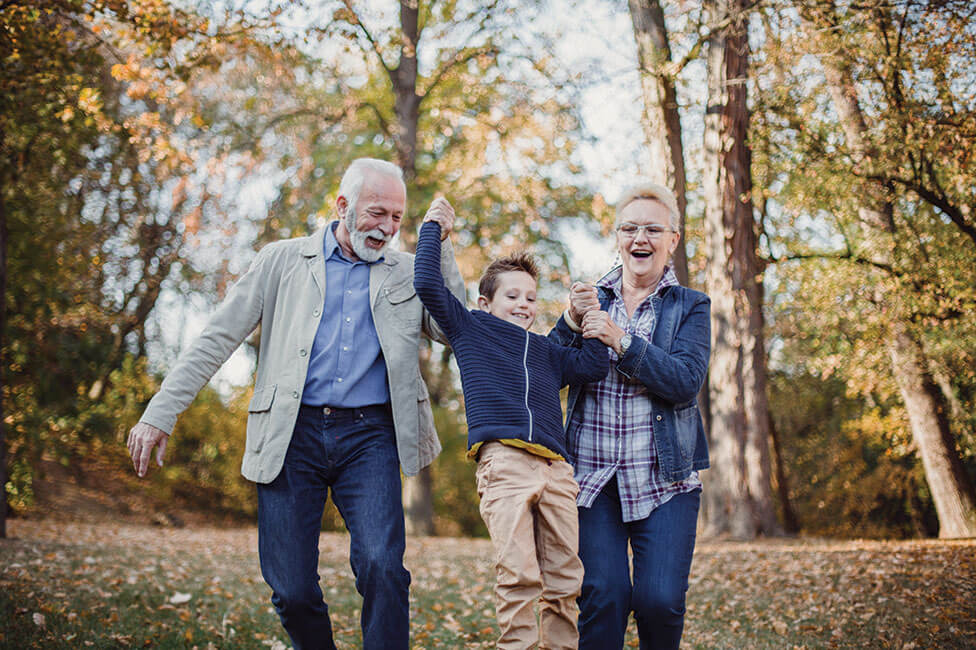 Caucasian grandparents lifting a grandson of the ground as they walk in the park