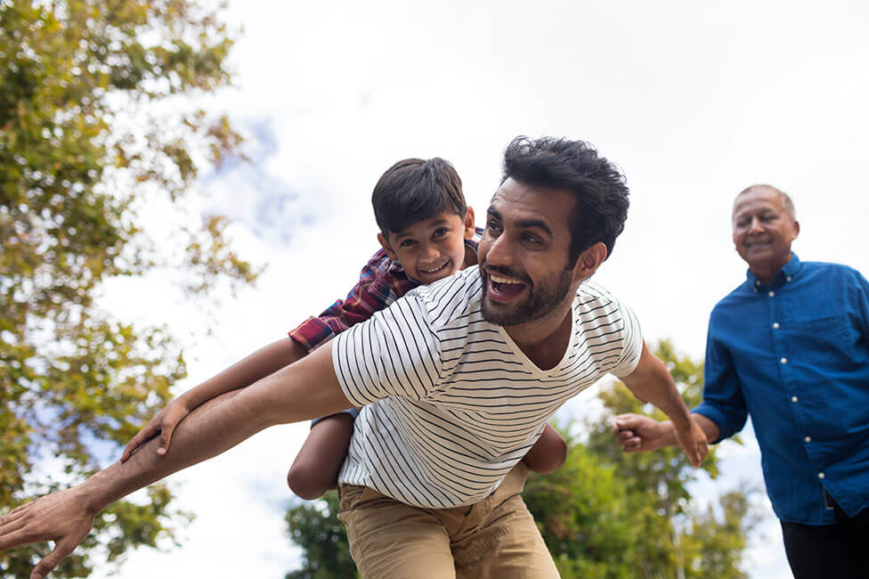 young boy on his dad's shoulders pretending to fly like an airplane