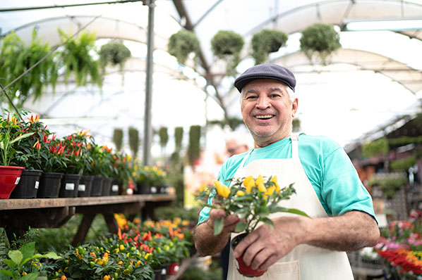 man at flower nursery holding a pot of flowers