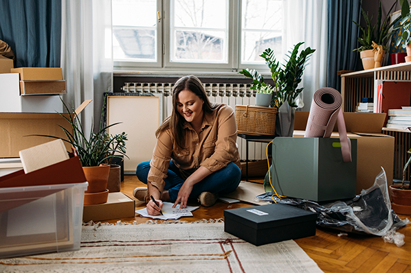 Lady sitting on floor smiling with moving boxes