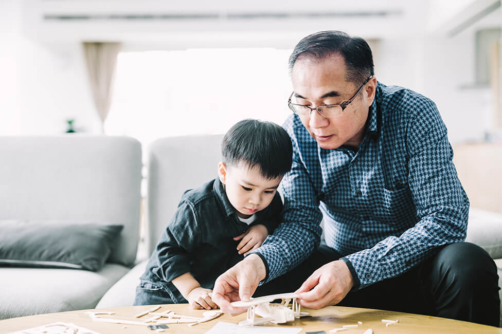 young boy and grandpa building a wooden toy plane