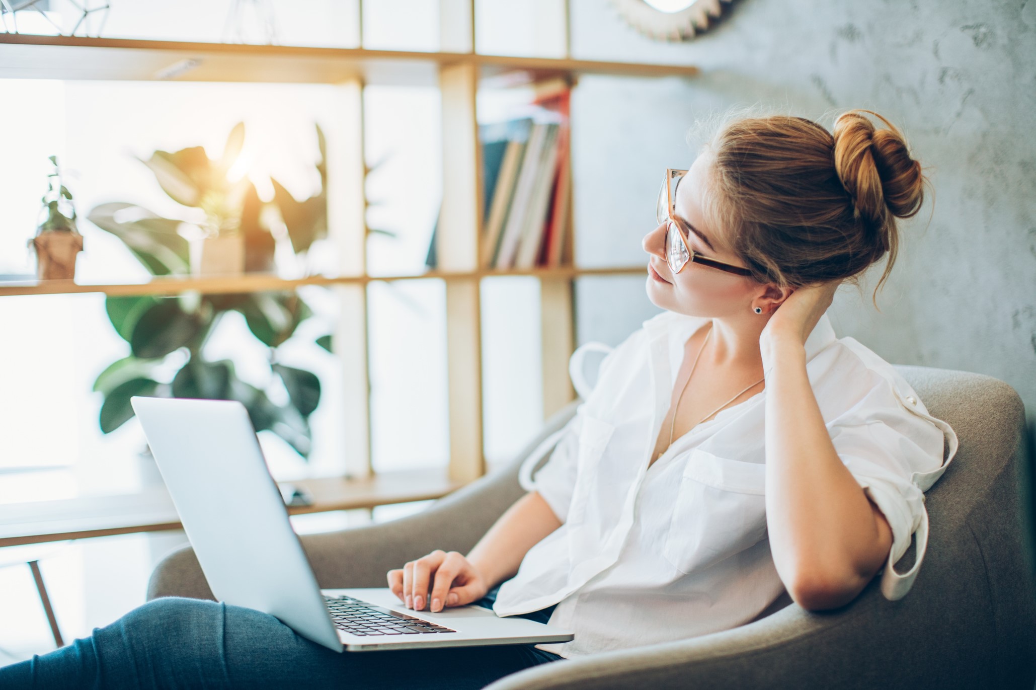 young woman sitting in an armchair with her laptop