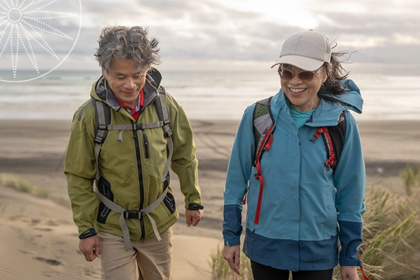 couple walking on beach in windbreaker jackets