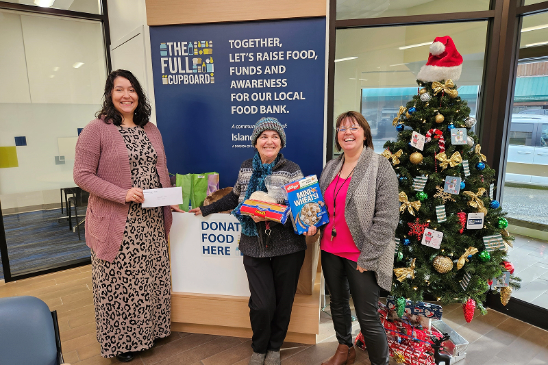 Three women holding gifts next to a Christmas tree