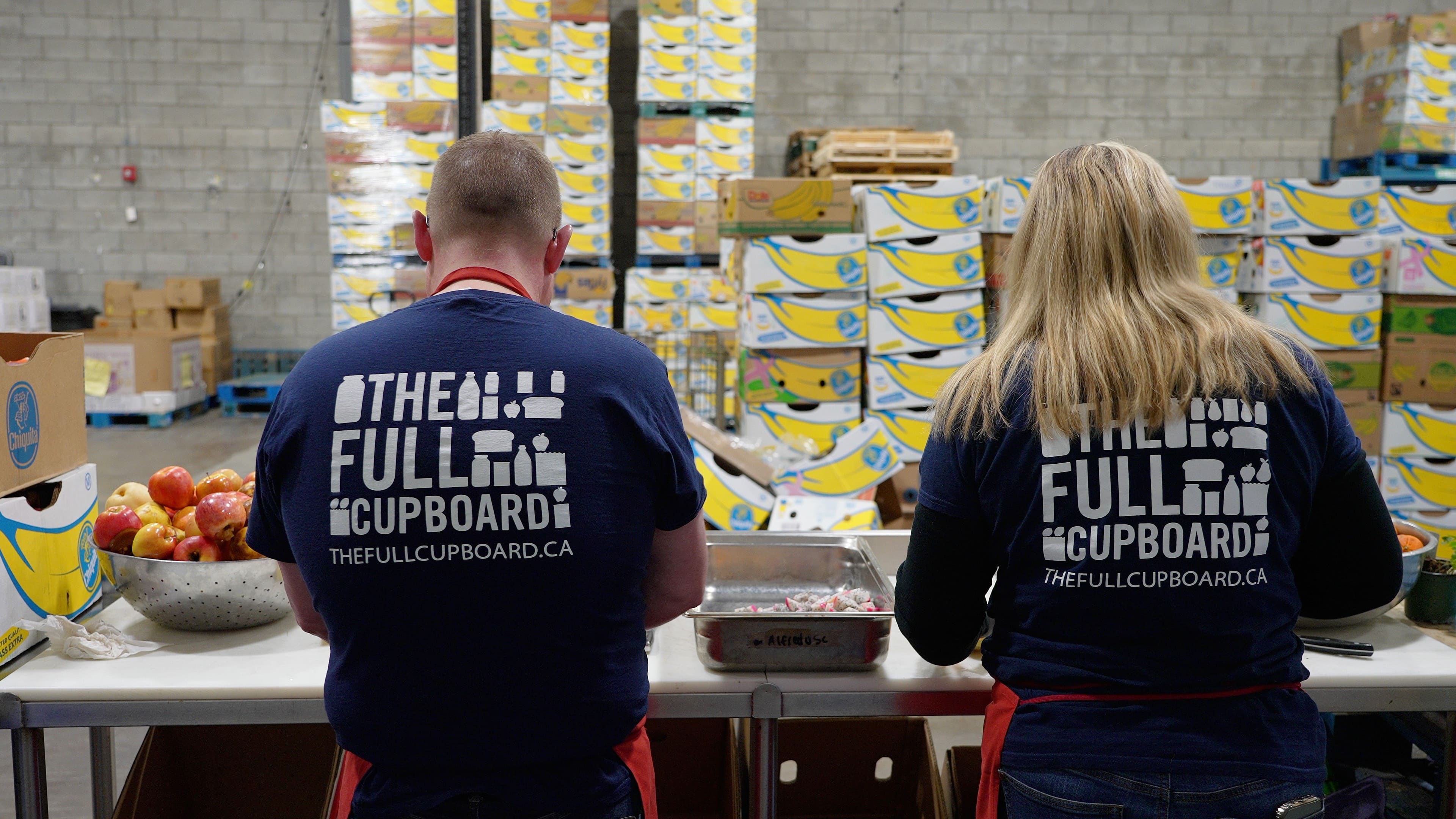 A man and woman sorting through food to pack
