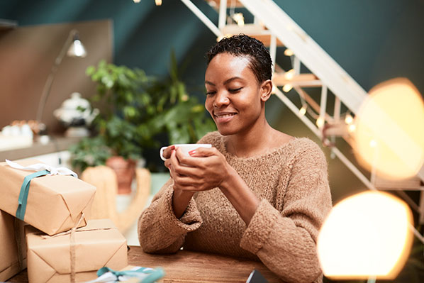 young black woman having tea while wrapping presents
