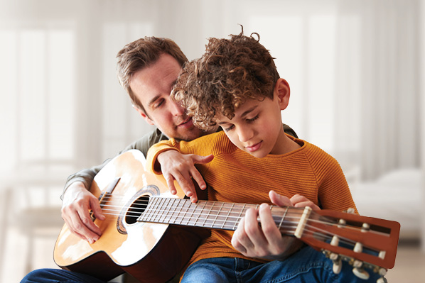 dad teaching boy to play the guitar.jfif