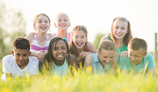 kids lying down in the grass looking at the camera smiling