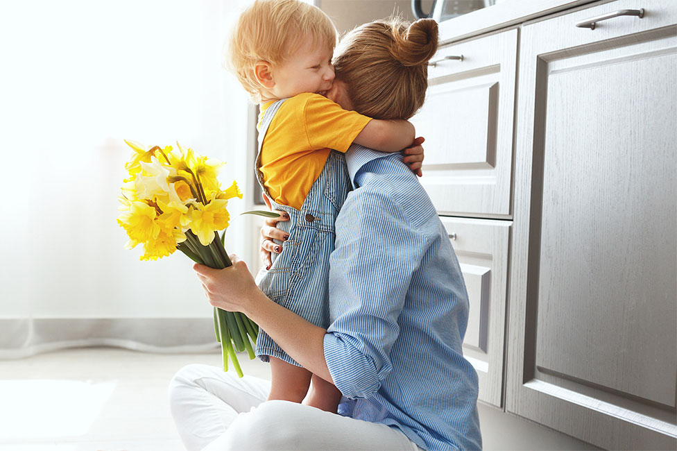 mom hugging child while holding daffodils.jpg