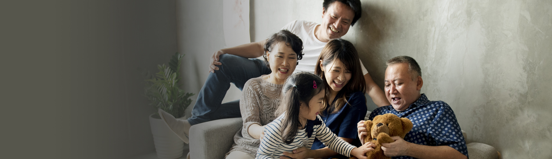 multigenerational Asian family sitting on the couch laughing with grandpa