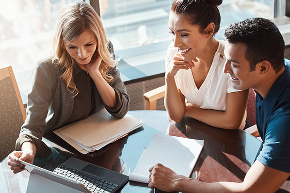 young couple sitting at a table with their advisor going over their plan